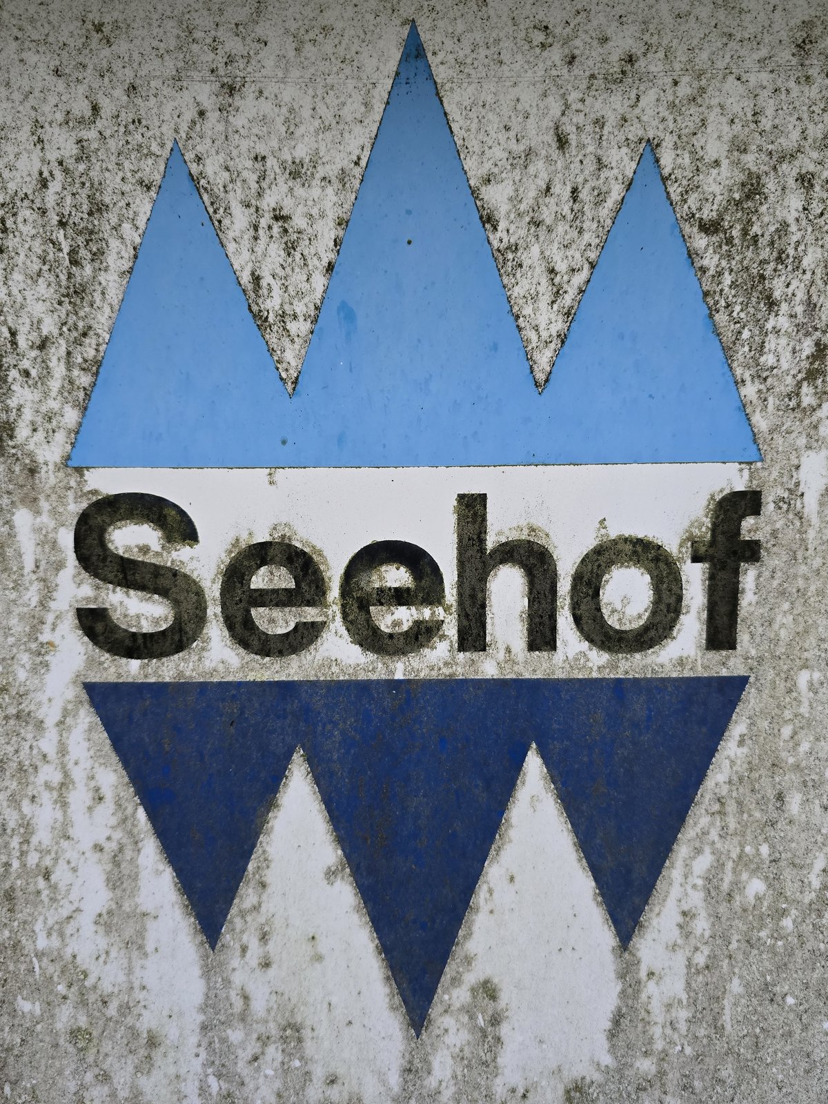 Das verwitterte Seehof-Emblem auf Beton — Schriftzug wartet auf Erweckung