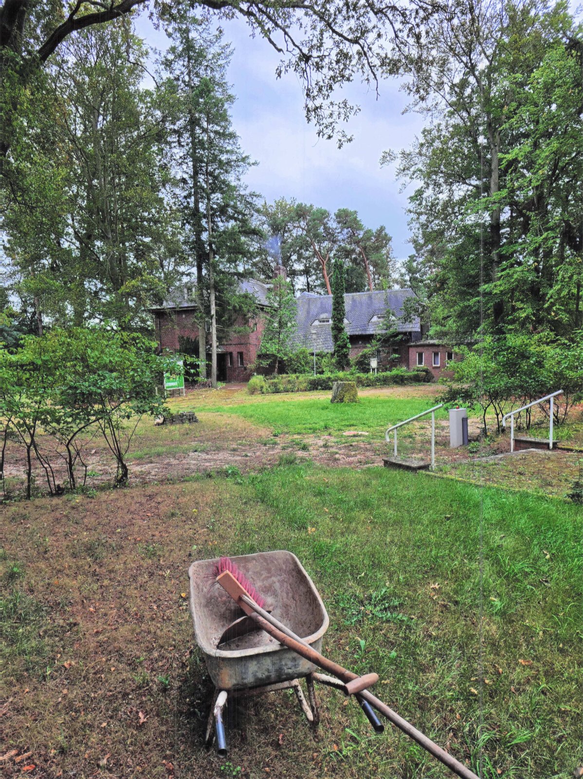 Schubkarre im verwilderten Garten — Waldhotel Seehof im Hintergrund