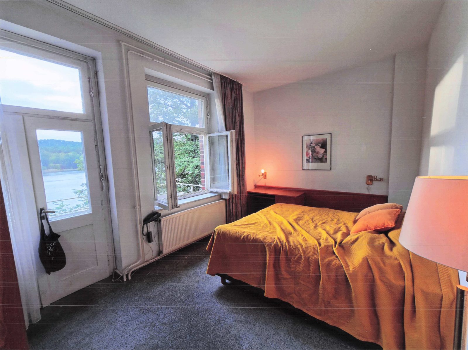 Hotelzimmer mit orangefarbenem Bettüberwurf und Seefenster I